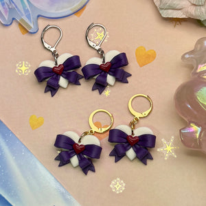 Heart-shaped earrings with purple bows and red hearts on a decorative background