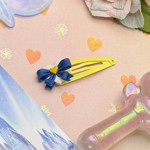 Yellow hair clip with blue bow on a decorative background with hearts and stars
